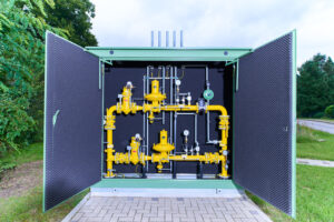 Geöffnete Gasdruckregelstation mit gelben Rohrleitungen im Grünen