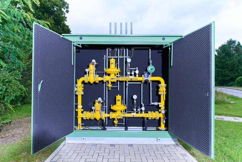 Geöffnete Gasdruckregelstation mit gelben Rohrleitungen im Grünen